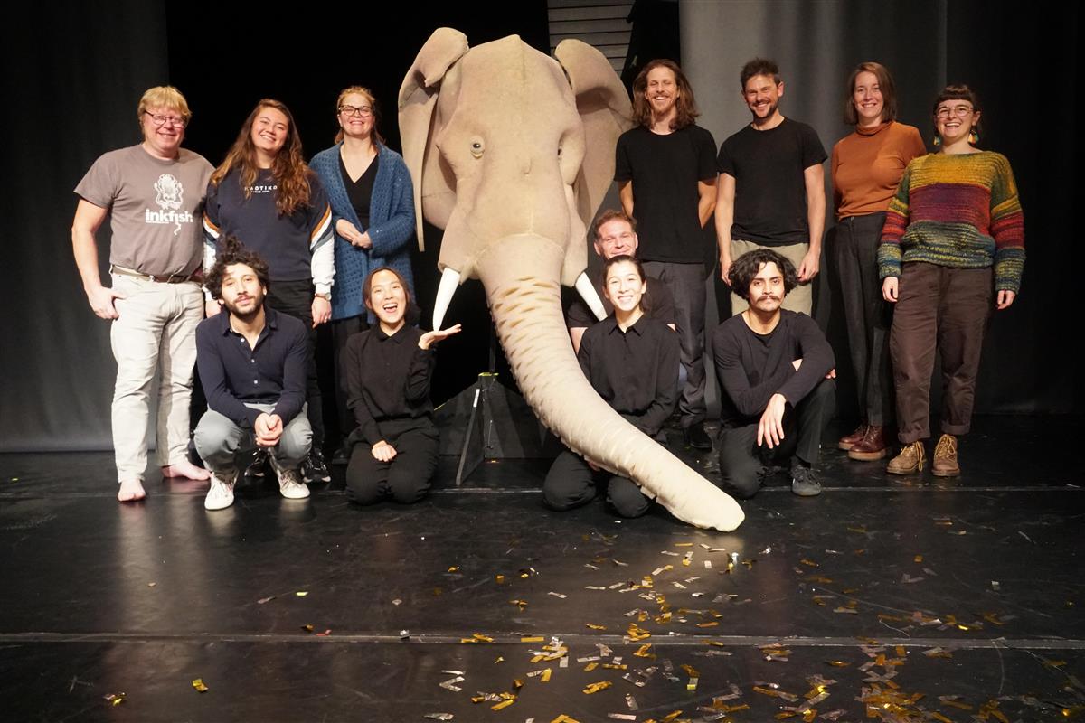 Personer og en elefantdukke står sammen på scenen - Klikk for stort bilde