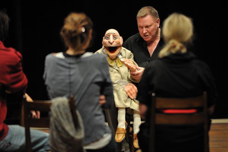 Mann med dukke spiller foran deltakere på workshop - Klikk for stort bilde